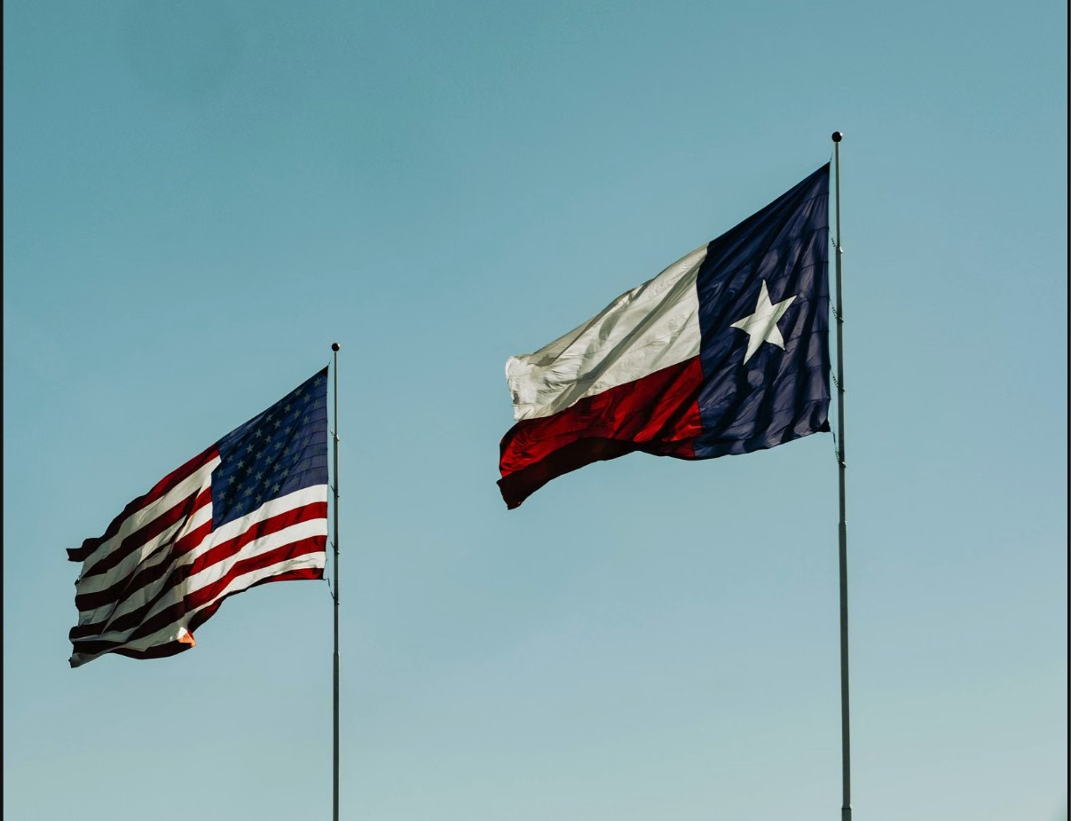 American and Texas flags flying against a clear sky in Fort Worth, Texas